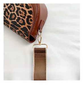 Detailed close-up of golden metal hardware on leopard print saddle bag with woven strap
