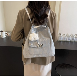 Detail of silver pleated fabric backpack with butterfly charm and fluffy pendant decoration