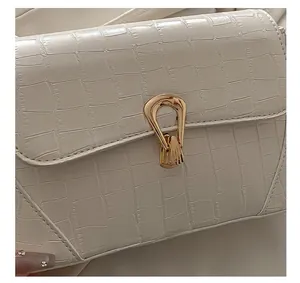 Close-up of cream embossed faux crocodile leather with elegant golden metal twist lock