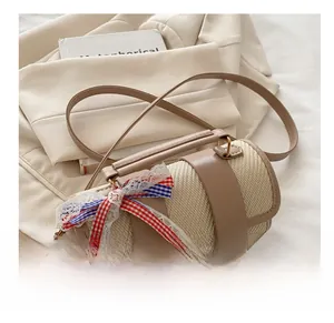 Close-up of woven straw handbag featuring leather trim and decorative lace bow detail