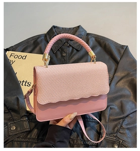 Detail of pink woven texture flap and golden hardware on the versatile crossbody bag