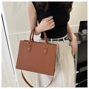 Brown faux leather tote bag with double handles and adjustable strap shown on model
