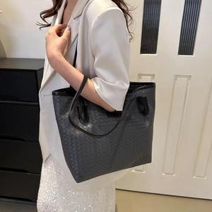 Detail of grey woven tote bag featuring diamond weave pattern and leather trim