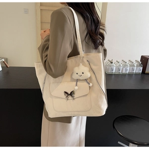 Detail of cream tote bag with silver butterfly buckle and cloud plush charm