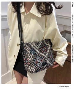 Détail d'un sac cabas tissé multicolore avec motifs géométriques et bandoulière en cuir