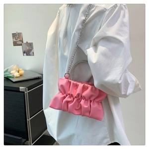 Detailed view of pink pleated handbag featuring a sparkling rhinestone handle and silver chain