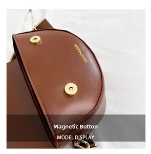 Detail shot of the magnetic snap closure and gold lettering on brown leather saddle bag