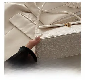 Close-up of precise stitching on cream faux crocodile leather bag with gold buckle