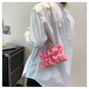 Detail of pink pleated cloud bag with rhinestone handle and silver chain strap