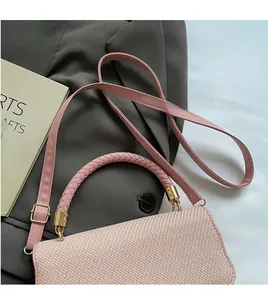 Detail of pink woven handbag with golden metal buckles and detachable shoulder strap