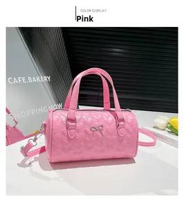Vista detallada del bolso cilíndrico rosa con acolchado de corazones y lazo plateado