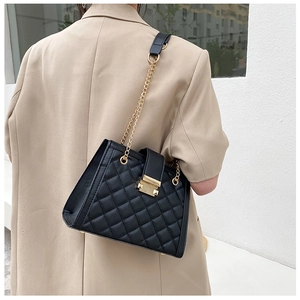 Detailed view of black quilted leather shoulder bag with gold chain and metal clasp