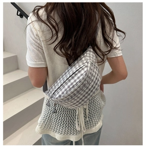 Detail of grey plaid saddle bag with double metal zippers on a stylish crossbody strap