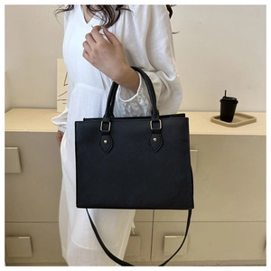 Detail of black crossgrain faux leather tote bag with gold metal hardware for business use