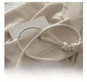 Detail shot of the beige crocodile-patterned strap with decorative knot on a square bag