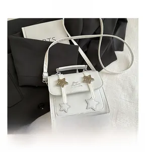 Detailed view of white square crossbody bag with star accents and top handle