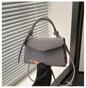 Détail d'un sac à bandoulière à motifs avec poignée nouée et finitions dorées chic