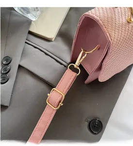 Close-up of pink woven handbag with premium gold-tone metal hardware and leather strap