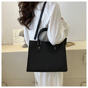 Detail view of the black textured leather business tote with golden hardware on a model