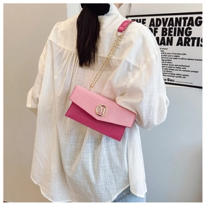 Sac bandoulière bicolore rose avec logo M doré et chaîne porté par un mannequin