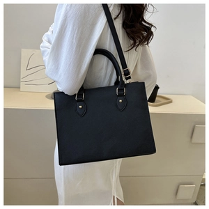 Detail of black pebbled leather tote bag with gold hardware and removable shoulder strap