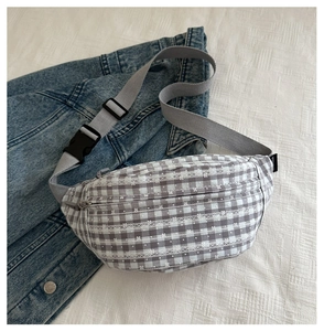 Detail of gray plaid canvas waist bag with white lace floral texture and adjustable strap