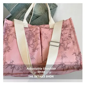 Detailed view of pink tote bag with brown bamboo leaf patterns and adjustable strap