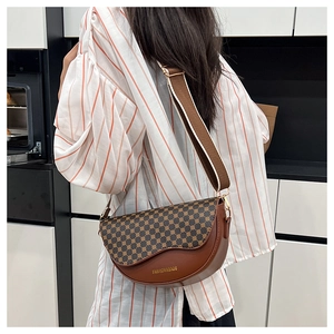 Detail view of a vintage saddle bag with brown monogram pattern and wide woven strap