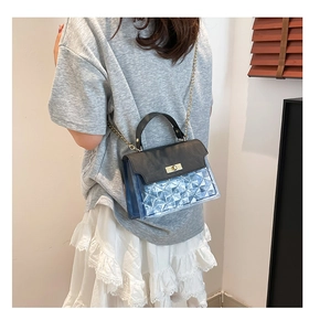 Detail of blue PVC crossbody bag with geometric texture and gold twist lock closure