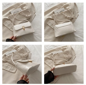 Detail view showing crocodile texture and gold clasp on the white underarm baguette bag