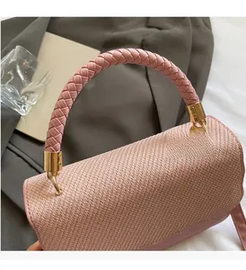 Close-up of pink woven handbag featuring braided handle and gold hardware detail