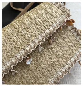 Detailed close-up of woven straw bag with boho fringe tassels and seashell charms