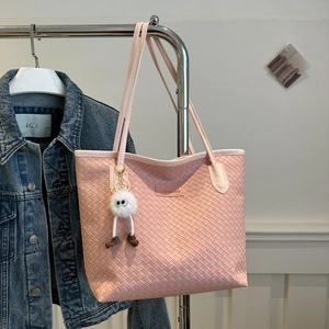 Pink woven tote bag detail with fashion label and white plush charm on metal hanger