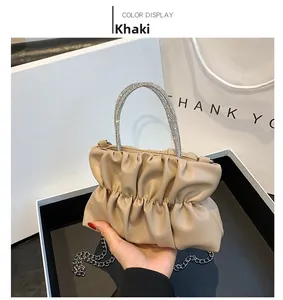 Detailed shot of khaki pleated cloud bag with rhinestone handle in a white gift box