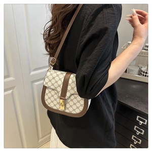 Detail view of a vintage saddle bag with chain pattern and gold metal buckle on shoulder