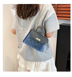 Close-up of quilted blue PVC and black leather crossbody bag with gold chain strap