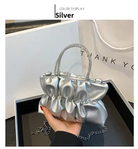 Close-up of silver pleated handbag with rhinestone handles and metal chain strap