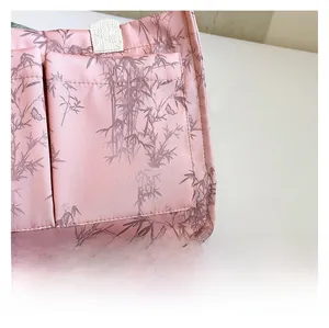 Detailed view of pink fabric tote bag with elegant brown bamboo leaf pattern and stitching