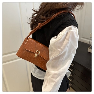 Détail du sac à bandoulière marron motif croco avec boucle dorée et lanière à nœuds