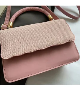 Close-up of pink shell-shaped evening bag with woven texture and gold hardware