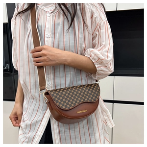 Detail view of a stylish brown saddle bag with vintage pattern and wide canvas strap