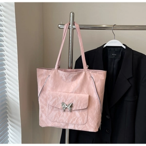 Detail of light pink tote bag featuring crinkled texture and silver butterfly buckle