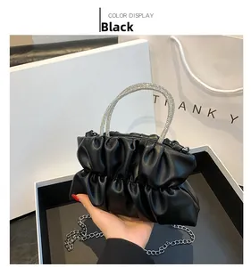 Detail of black pleated handbag with silver rhinestone circular handle and chain strap