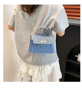 Close-up of blue geometric textured PVC handbag with metallic chain strap on model