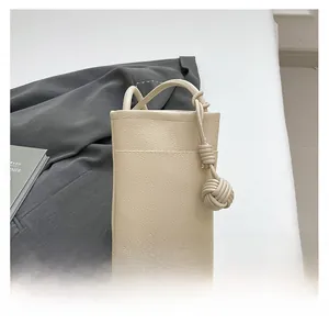 Detail der cremeweißen Ledertasche mit Litschi-Maserung und dekorativem Knotengriff
