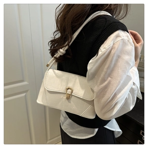 Détail d'un sac bandoulière blanc à motif crocodile avec un fermoir doré de luxe