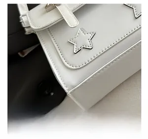 Close-up detail of precision stitching and star-shaped applique on white leather bag