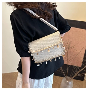 Detail of bohemian straw crossbody bag featuring white shell charms and adjustable strap