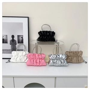 Detail of five colored pleated bags with crystal handles and chain straps in a home setting