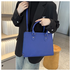 Blue lychee faux leather tote bag being carried by a model in a professional suit